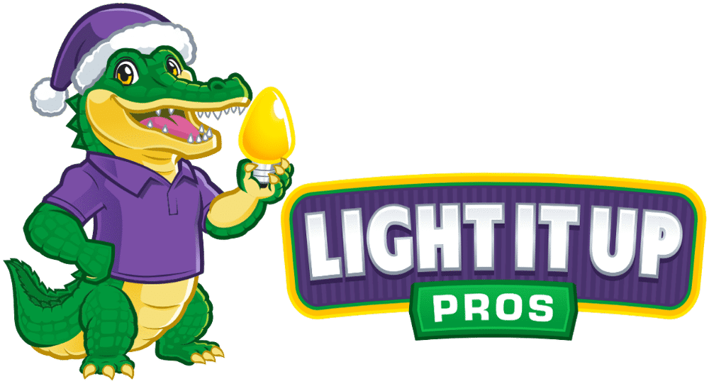 Cartoon alligator wearing a Santa hat and a purple polo shirt, holding a yellow lightbulb. To the right is a logo that says "LIGHT IT UP PROS".